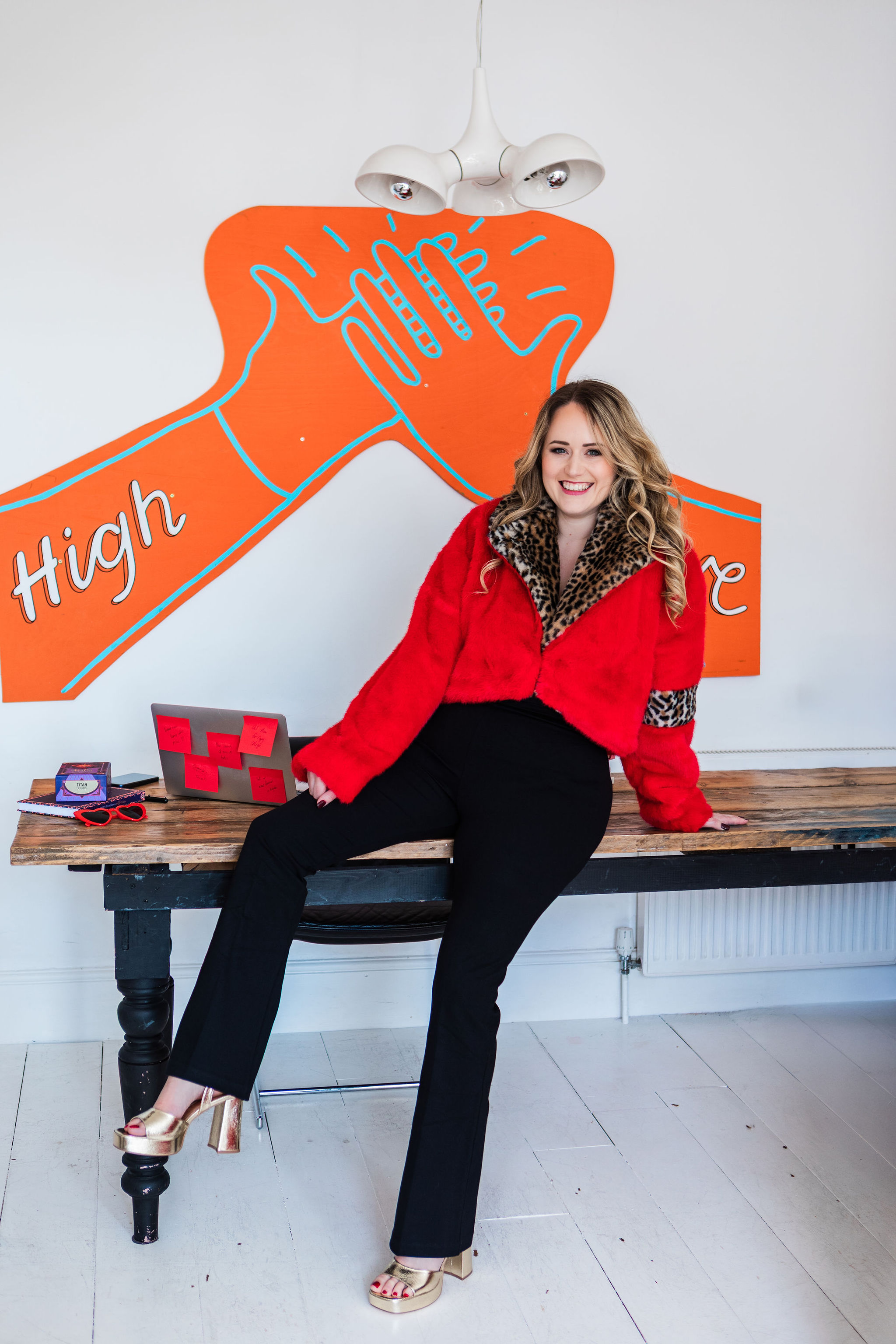 Chantelle in a red faux-fur jacket in front of a high-five mural